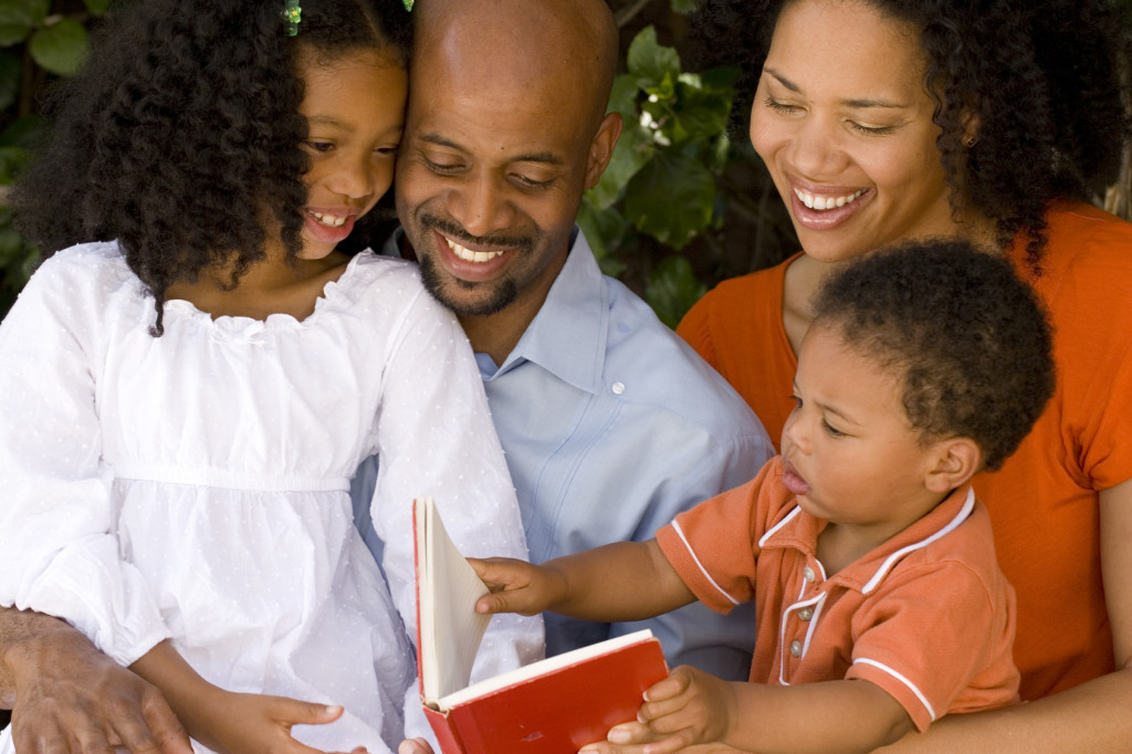 Loving African American parents reading with their kids.