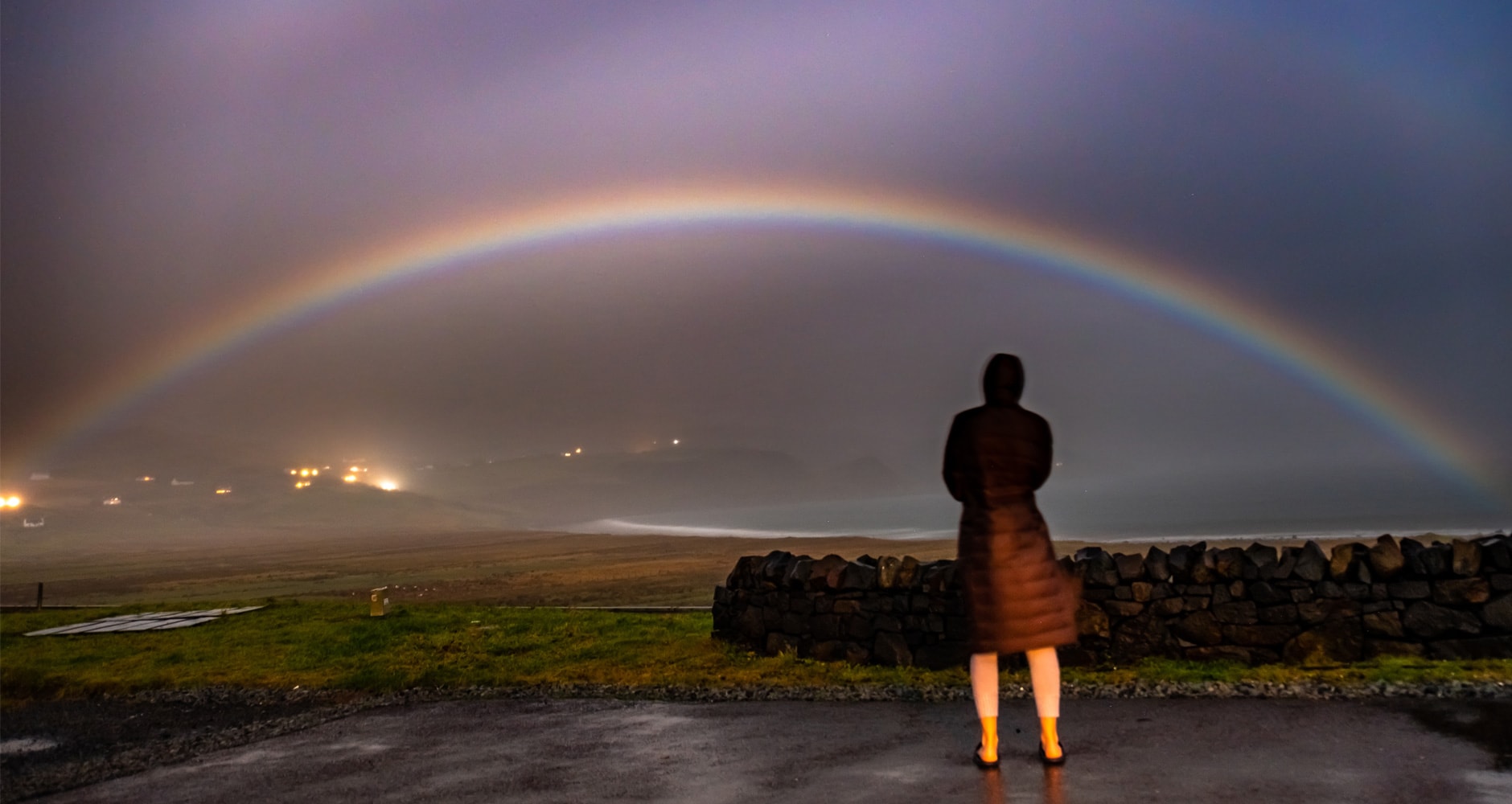 Person in coat watching moonbow.
